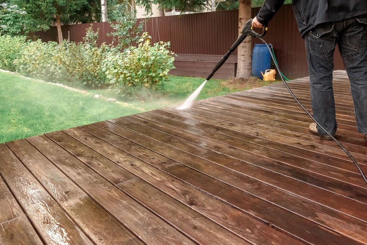 A person using a hose to clean the deck.