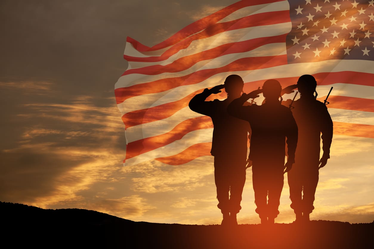 Three soldiers saluting in front of an american flag.