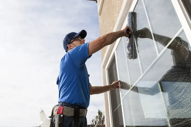 Man cleaning window of a home.