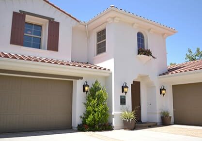 A white house with two garage doors and windows.