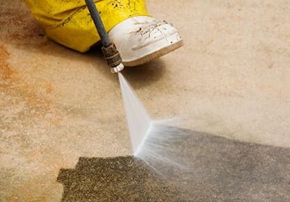 A person using a high pressure washer on the floor.