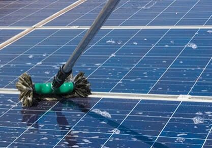 A mop is on the ground cleaning solar panels.